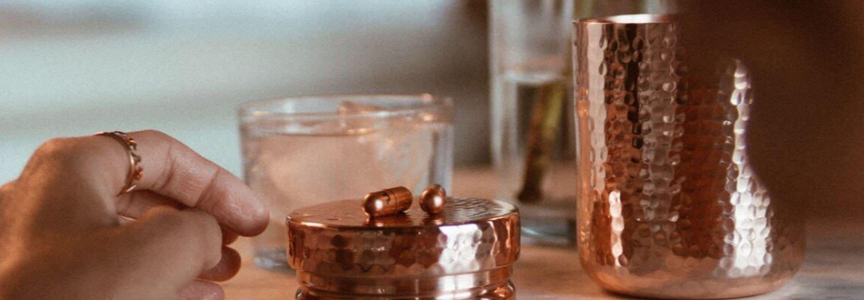Boost mood copper pill container near water glass